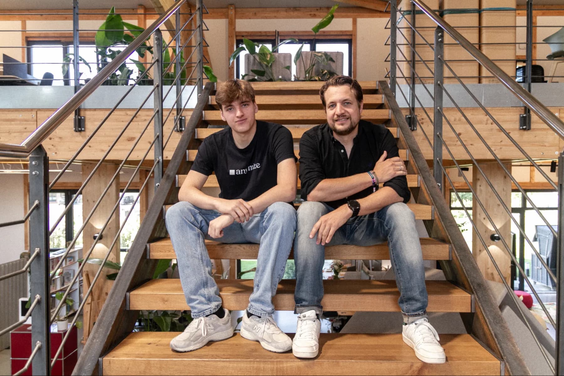 Nikolai und Raitschin Raitschew, die Gründer von anymize, sitzen nebeneinander auf einer Holztreppe im Büro